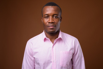 Obraz premium Studio shot of young African businessman against brown backgroun