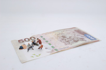 a mini beggar begs on bank note