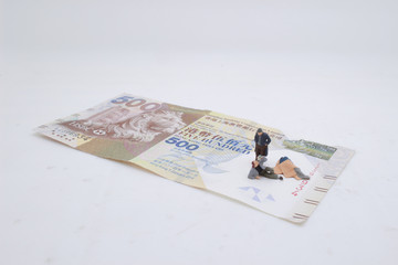 a mini beggar begs on bank note