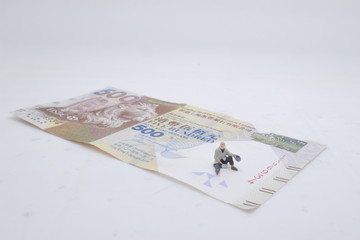 a mini beggar begs on bank note