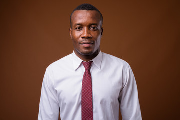 Studio shot of young African businessman against brown backgroun
