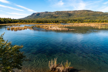 Alaskan landscape in fall color, Brooks River with spawning salmon, Dumpling Mountain and blue sky, Katmai National Park, Alaska, USA

