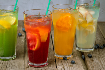 different lemonades in glasses on wooden background