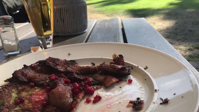 Table view of potato pancake with crispy fried pork and lingonberries served outside a lovely summer eavning.