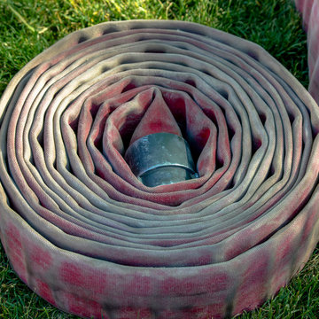 Coiled Fire Hose On A Grassy Ground