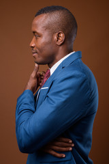 Studio shot of young African businessman against brown backgroun