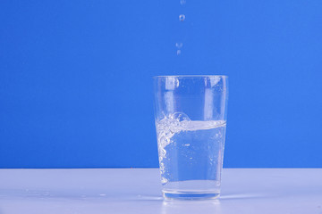 Water splashing from glass isolated on a blue background.