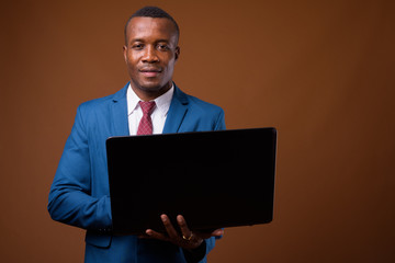 Studio shot of young African businessman against brown backgroun