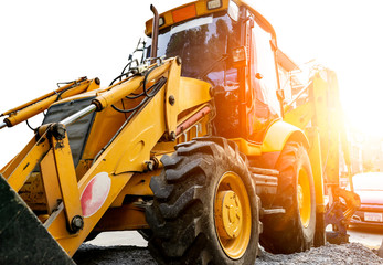 Yellow backhoe parking at construction site in the morning