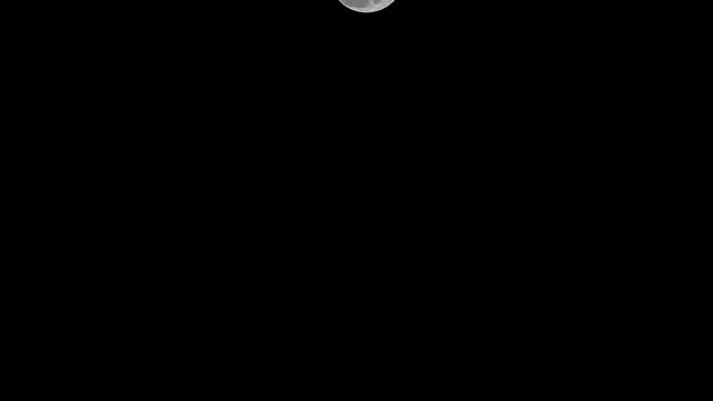 Beautiful full moon shining bright on dark night sky, camera tilt down.