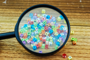 Small dice alphabet and glass magnifier. Search for keyword concept
