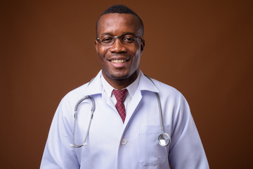 Studio shot of young African man doctor against brown background