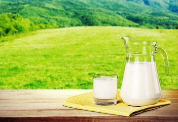 Glass of milk and jar on table