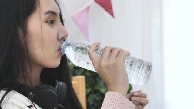 Slow motion of asian beautiful woman drinking water from bottle be delighted at home .