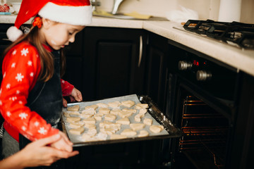 Girl putting cookies to stove