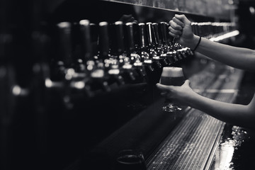 black and white row of beer taps with arms and full glass