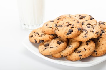Chocolate chip cookies next to a glass of milk