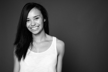 Young Asian woman against gray background in black and white