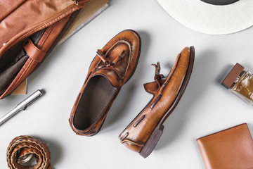 Top view of vintage brown tassel loafers and leather accesories on grey background, business casual...