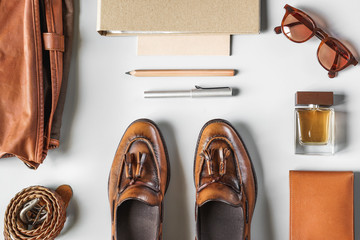 Top view of vintage brown tassel loafers and leather accesories on grey background, business casual items