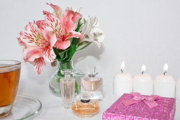 Image of a pink luxury gift box with a bouquet of beautiful Alstroemeria flowers, a romantic candle and perfume, a festive still life, lit candles. Greeting card concept.