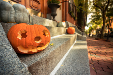 A scary carved pumpkin Jack o Lantern on the steps of a home before Halloween trick or treat