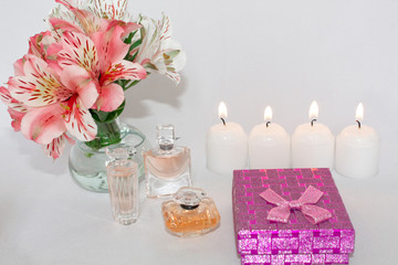 Obraz na płótnie Canvas Image of a pink luxury gift box with a bouquet of beautiful Alstroemeria flowers, a romantic candle and perfume, a festive still life, lit candles. Greeting card concept.