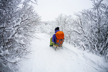 A woman on a sled rides from the mountain.