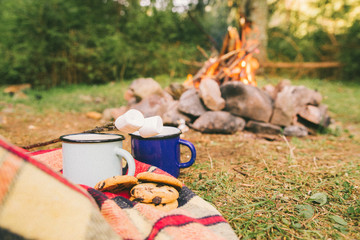 two metal cups with tea and cookies. fire on background