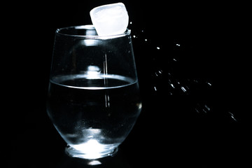 icecube with glass of water on black background