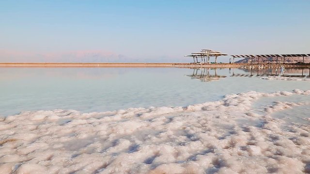 Dead Sea coastline with salt beach, mountains, and  wooden shelter gazebo, Israel, Middle East.