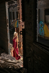 Woman playing with her red dress in abandoned train hall
