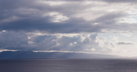 Fototapeta premium Sunlight ray though the cloud and sea under sunset