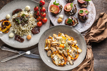 Spaghetti with pesto, salad with mussels and canapes with tomatoes. Mediterranean Kitchen.