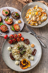 Fototapeta na wymiar Spaghetti with pesto, salad with mussels and canapes with tomatoes. Mediterranean Kitchen. Vertical shot