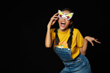 Young tan asian pigtail woman in Butterfly mask wearing  yellow t-shirt,  jeans dungarees and acting face 