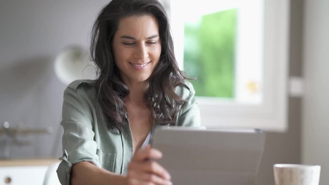 Brunette woman  sitting at a table looking at her tablet