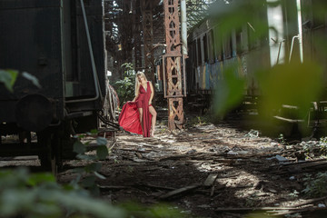 Fototapeta na wymiar Woman posing on abandoned train station in a red dress