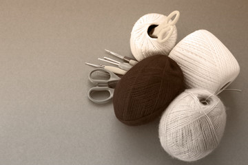 Balls of yarn, knitting needles, scissors, crochet hooks. Materials and tools for needlework. The concept of earning needlework.  Image in sepia tones.
