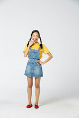 Isolate young tan Asian woman wearing yellow t-shirt, jeans dungarees and expressive facial on white background