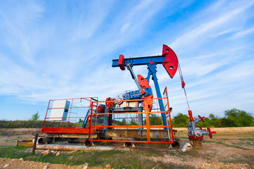 Fototapeta na wymiar The oil pump, industrial equipment. Oil field site, oil pumps are running. Rocking machines for oil production in a private sector.