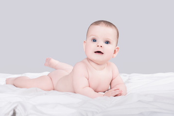 cute little baby girl or boy lying on soft blanket isolated on grey