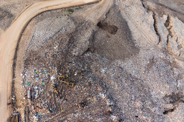 Aerial top view from drone. Modern hydraulic excavator on a field work site where an excavation works is performed in Garbage pile in trash dump or landfill.