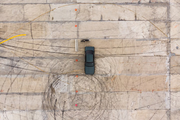 Aerial top-down view of car on drift training track with visible tire marks and skid patterns on...