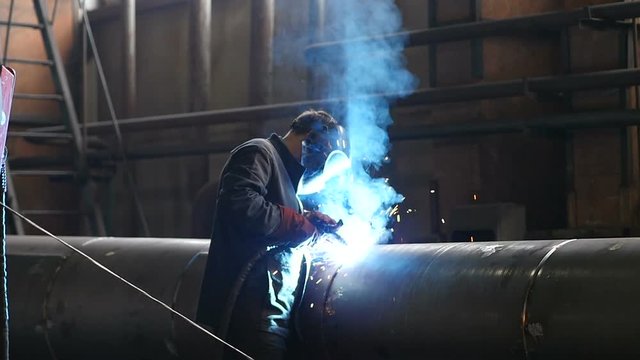 Man welding metal tube in plant