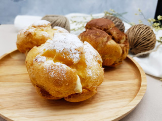 Chocolate and vanilla choux cream puff on wooden plate