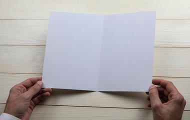 Mens hands holding empty white booklet