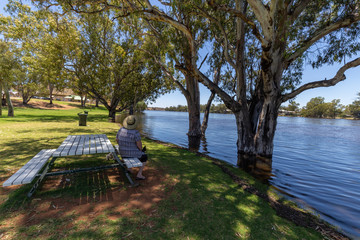 Mature women sitting at park bench enjoying the view of the Murray River at Morgan in South Australia in flood.