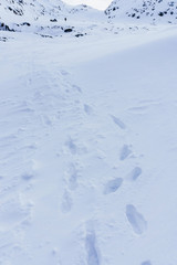 following a shoe in deep snow after a snowfall during a transition through the mountains and rocks