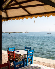 griechische Taverne mit Sonnenschirm, Tisch und Stühlen am Mittelmeer in der Nachsaison